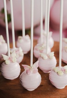 there are many white cake pops with pink bows on them in the shape of butterflies