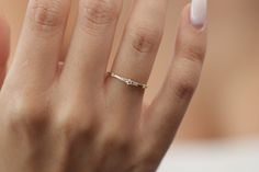 a woman's hand with a diamond ring on her left hand and white nails