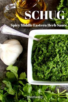 a white bowl filled with green pesto next to garlic and parsley