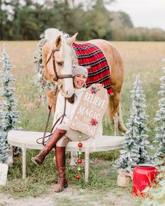 a woman sitting on a bench next to a horse wearing a blanket and holding a sign