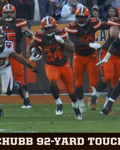 a group of football players running on top of a field with fans in the background