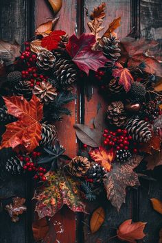 a wreath with pine cones, berries and other autumn leaves on a wooden door frame