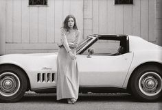 a woman standing next to a white sports car