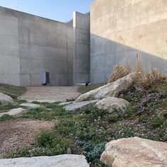 there is a rock and grass area in front of a building that has been built into the concrete