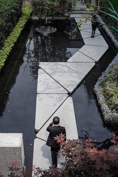 a man in a suit is walking through the garden