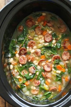 a crock pot filled with sausage, beans and spinach