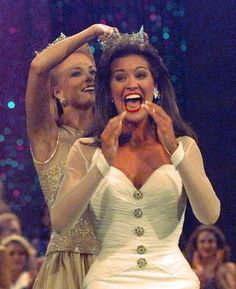 two women dressed in wedding gowns and tiaras, one holding her hands up to her mouth