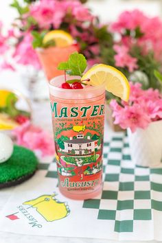 a pink drink sitting on top of a checkered table cloth next to potted flowers