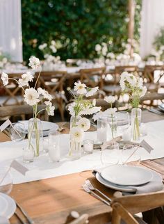 there are many vases with flowers in them on the table at this wedding reception