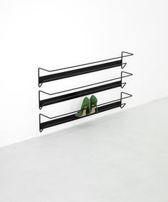 a pair of green high heeled shoes sitting on top of a black metal shelf