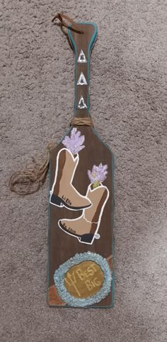 a wooden sign with an image of a boot and flowers hanging from it's side