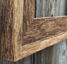 an old wooden frame is hanging on the side of a building with weathered paint and wood grain