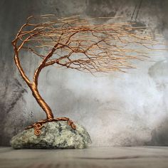 a wire tree sculpture sitting on top of a rock