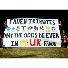 a group of people holding up a sign in front of a field at night time