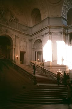 people are walking up and down the stairs in an old building with sunlight streaming through