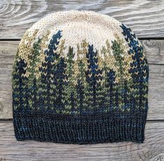 a knitted hat with trees on it sitting on top of a wooden table next to a