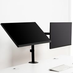 a desk with a monitor and keyboard on it next to a wall mounted computer screen