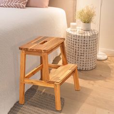 a small wooden step stool next to a bed