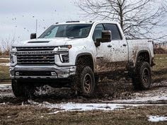 a white truck is driving through some mud