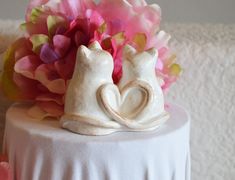 a white cake with flowers and two cats on it's side, sitting on top of a table