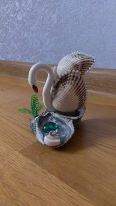 a white swan figurine sitting on top of a wooden table next to a plant