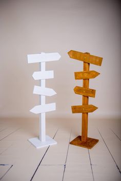 two wooden signs standing next to each other on top of a white tile floor in front of a beige wall