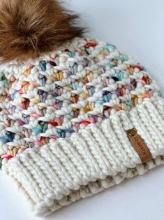 a white knitted hat with a brown pom - pom