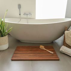 a white bath tub sitting next to a wooden tray with a toothbrush on it