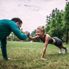 a man and woman doing push ups in the grass