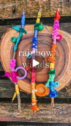 the rainbow wands are arranged on top of a tree stump with colorful ribbons around them