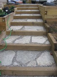 the steps are made from wood and have plants growing on them, along with concrete pavers