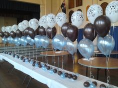 there are many balloons on the table in this room with white and brown tablescloths