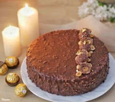 a chocolate cake sitting on top of a white plate next to two candles and some candies