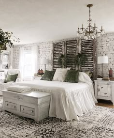 a bedroom with white brick walls and green pillows on the bed, along with an area rug