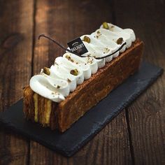 a piece of cake with whipped cream on top sitting on a black slate platter