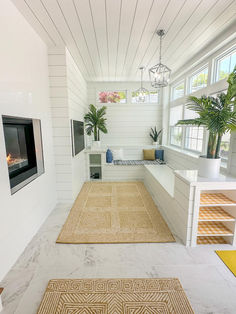 a living room with white walls and flooring next to a window filled with potted plants