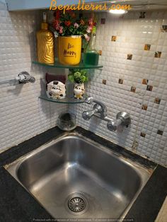 a stainless steel sink in a kitchen with shelves above it and flowers on the wall