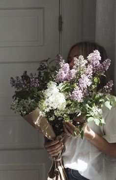 a woman holding a bouquet of flowers in front of a garage door with the sun shining through