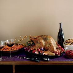 a table with food and wine on it, including a large turkey sitting on a platter