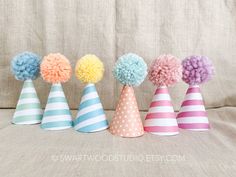 five party hats with pom - poms on them are lined up in a row