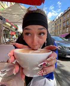 a woman holding a cup of coffee in front of her face