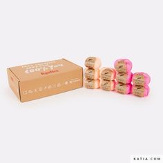 the box is full of pink and gold wrapped wine corks next to it's cardboard package