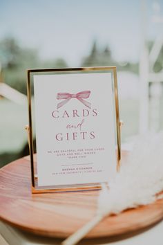 a card and gift sitting on top of a wooden table next to a white feather