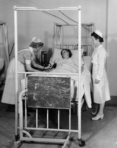 an old black and white photo of nurses tending to a patient in a hospital bed