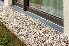 a close up of a window on the side of a building with rocks and grass