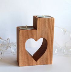 two wooden candlesticks with a heart cut out of them on a white surface