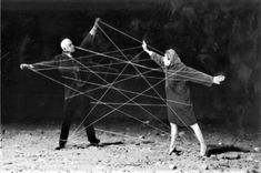 two people standing in the dirt with wires attached to their backs and arms as if they were trying to connect