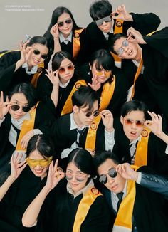 a group of young people wearing black and yellow graduation gowns with their hands in the air