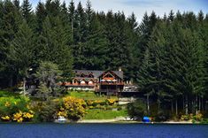 a large house sitting on top of a lush green hillside next to a body of water