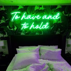 a neon sign that reads to have and to hold on the wall above a bed